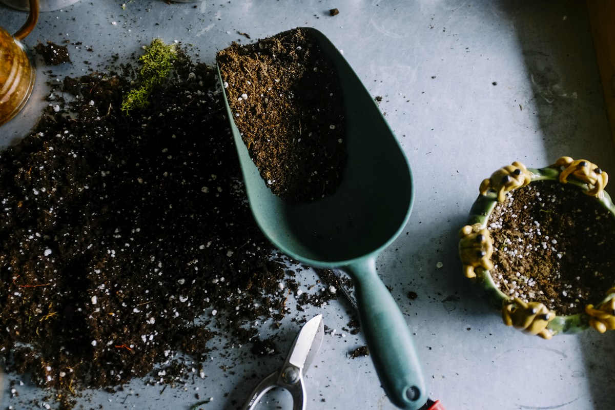 Potting soil, a garden trowel and planting pots on a gardener’s workbench